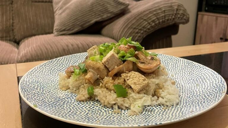 Button mushrooms and tofu served over garlic sesame rice on a plate