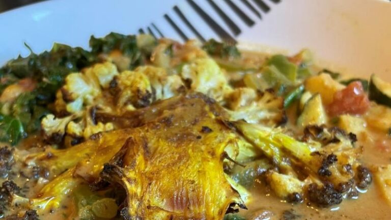Close-up of charred crispy cauliflower steak in coconut curry sauce