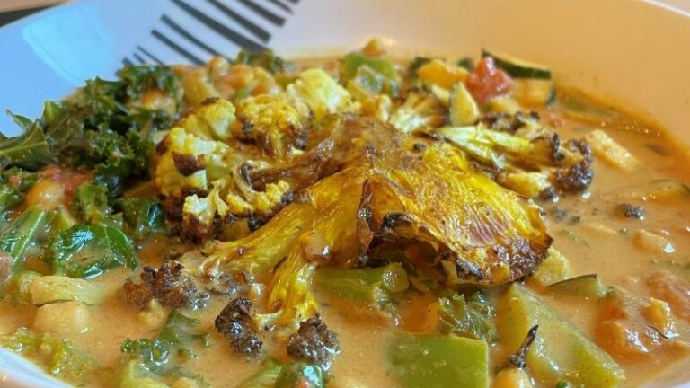 Crispy cauliflower steak with chickpeas, kale, courgette and coconut curry sauce