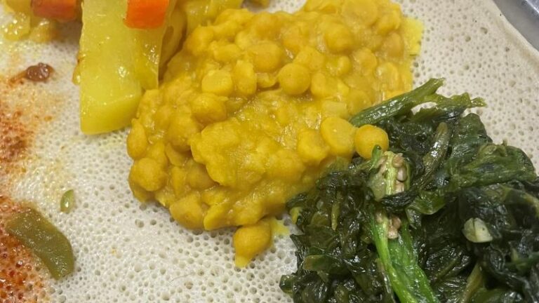 Close-up shot of chickpeas and greens on injera bread at Frehiwet Habesha in Sheffield