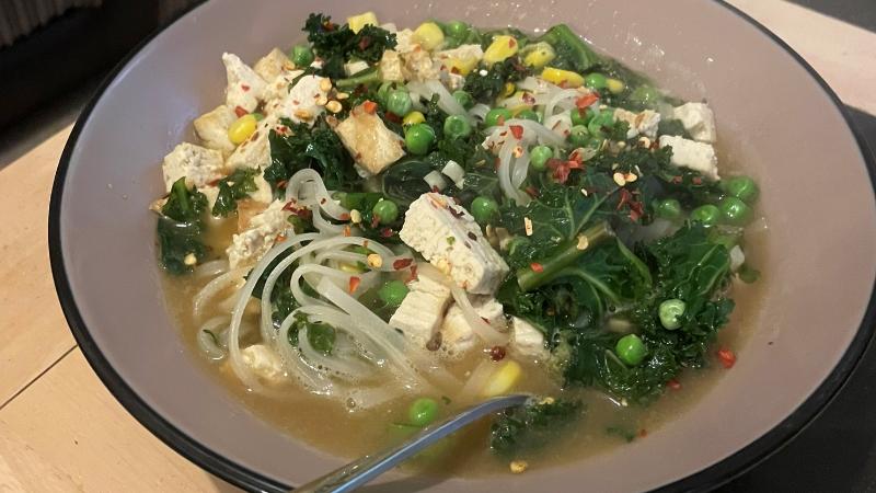 Homemade tofu ramen soup bowl with kale, peas, sweetcorn and noodles