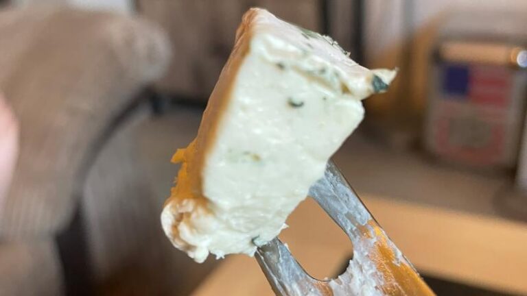 Close-up of Honestly Tasty Bree vegan cheese on a knife