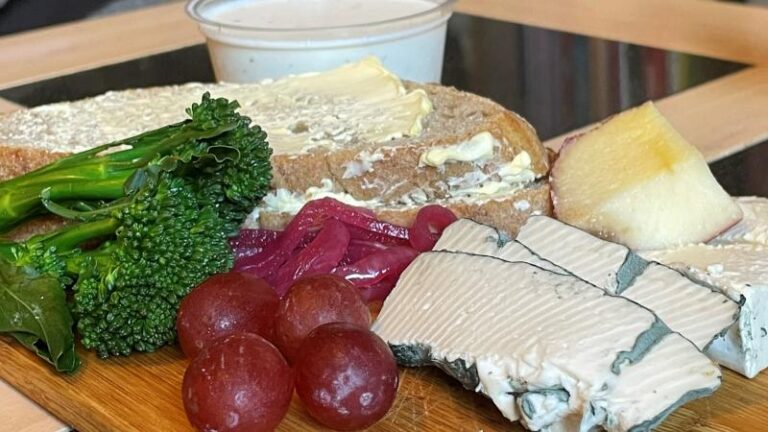 Close-up of a vegan cheeseboard with Honestly Tasty Blue, Bree, Garlic and Herb Dip, broccoli, grapes and bread