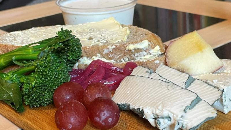 Close-up of a vegan cheeseboard with Honestly Tasty Blue, Bree, Garlic and Herb Dip, broccoli, grapes and bread