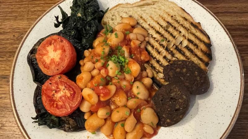 Vegan brunch at Honey + Harvey in Colchester with sourdough toast, posh beans, grilled tomato, spinach and vegan black pudding