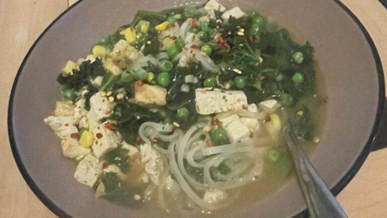 Simple tofu ramen soup with kale, peas, sweetcorn, rice noodles and chilli flakes