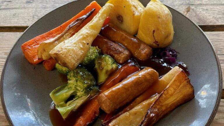 Full plate shot of a vegan roast dinner at Jacks at Woodlakes with sausages, roast potatoes, parsnips, carrots and broccoli