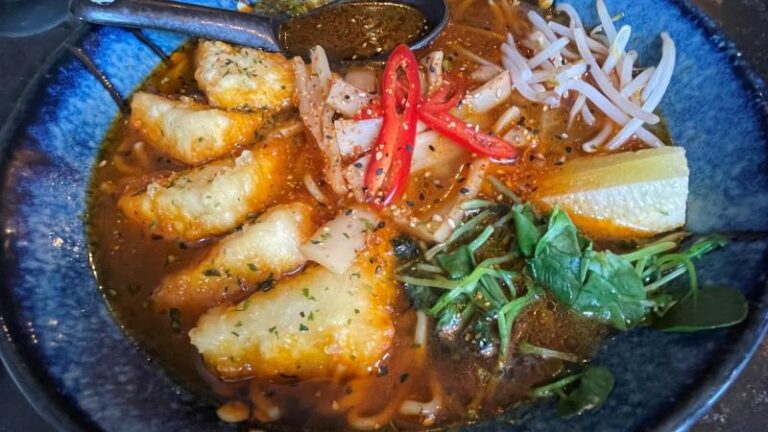 Close-up overhead shot of vegan spicy ramen soup at Koryu in Colchester with a spoon in the bowl