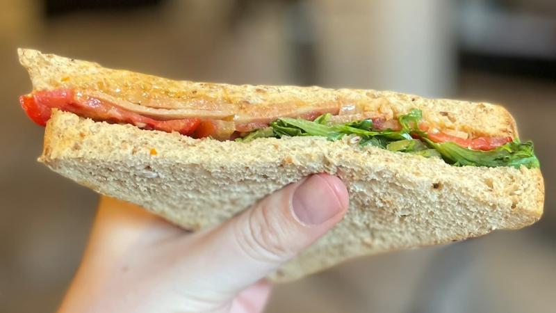 Shot of one half of a La Vie vegan VLT sandwich being held in hand