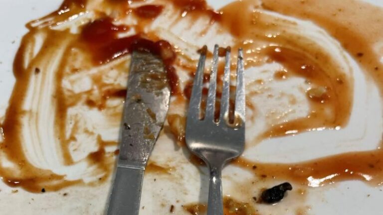 Finished breakfast plate at Mill Races in Aldham near Colchester with a knife and fork and leftover brown sauce