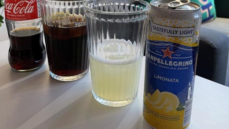 Bottle of Coca-Cola with a glass cup, and a can of San Pellegrino Limonata lemon with a glass cup at Piehole Pizzas in Southend