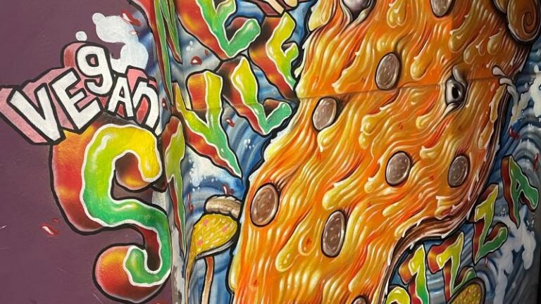 Picture of a graffiti-style painting at Piehole Pizzas in Southend saying vegan New York style pizza made especially for Piehole Pizzas