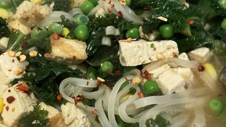 Close-up of simple tofu ramen soup with peas, kale, sweetcorn and rice noodles