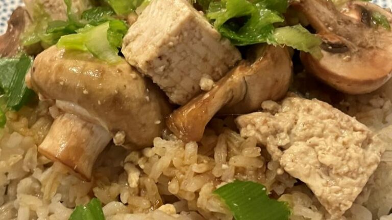 Close-up of steamed button mushrooms, tofu and spring onion on garlic sesame rice