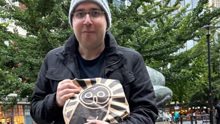 Ian holding a bag of food from The Athenian, showing the logo