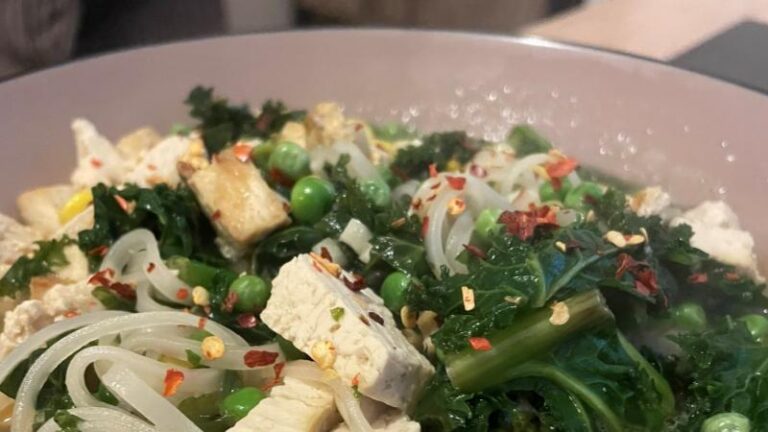Close-up of tofu ramen soup with kale, peas, noodles and chilli flakes