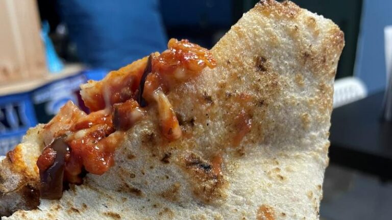 Close-up shot of vegan pizza crust and tomato sauce at UE Paisa in Hillsborough, Sheffield